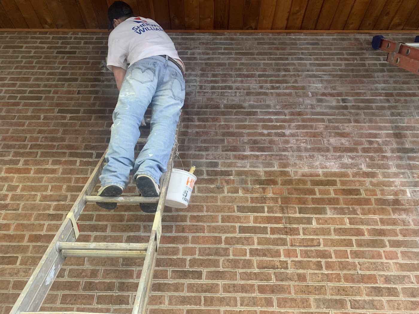 Advantage Painting crew member painting a brick wall on site